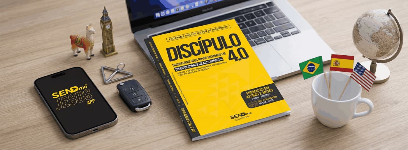 Mesa com notebook, livro amarelo Discípulo 4.0, celular com o app SENDme Jesus, globo e bandeiras do Brasil, da Espanha e dos Estados Unidos.